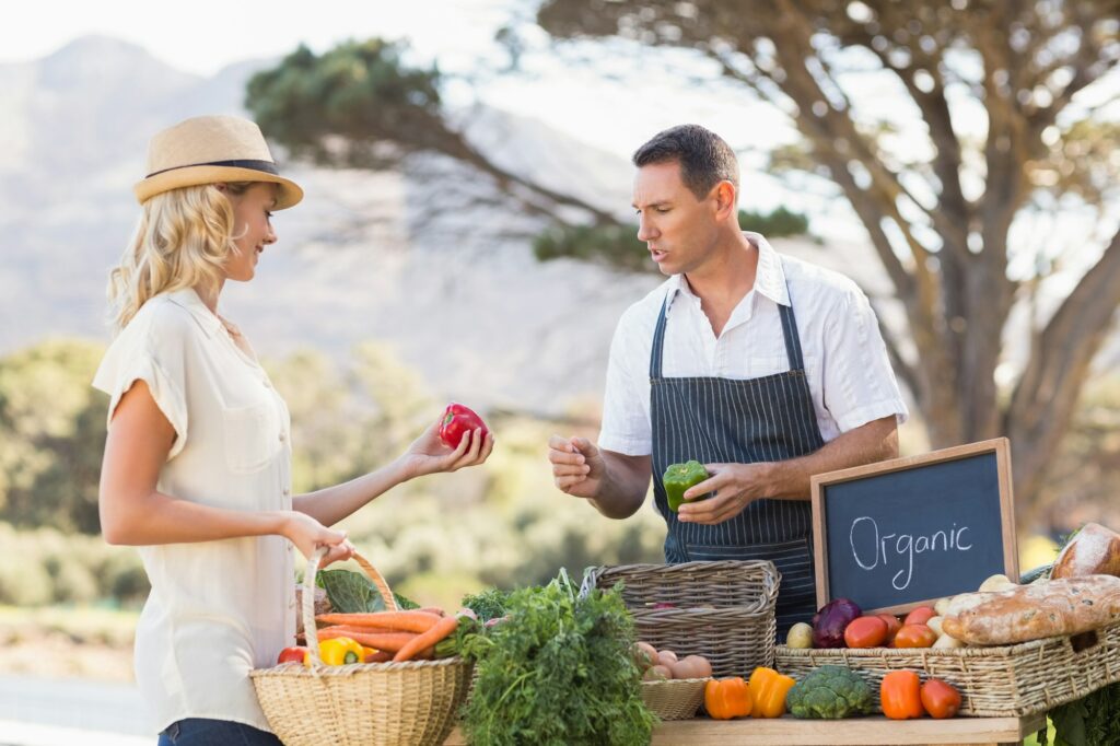 Farmer discussing with a customer at the local market - An Expat Mum’s Guide to Living an Eco-Friendly Lifestyle