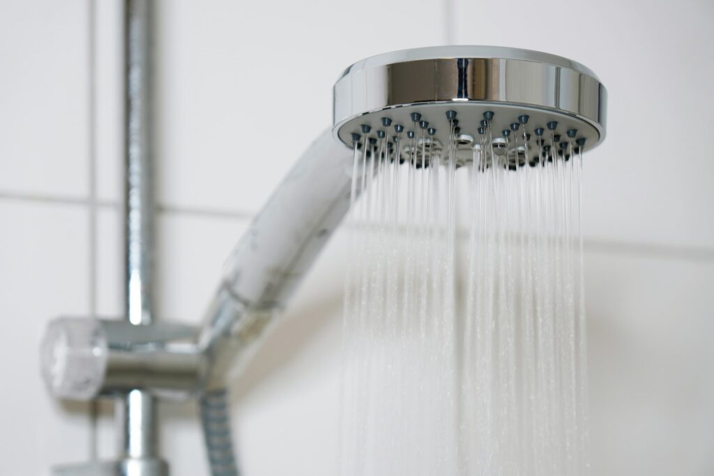 shower with modern showerhead and running water in domestic bathroom close-up